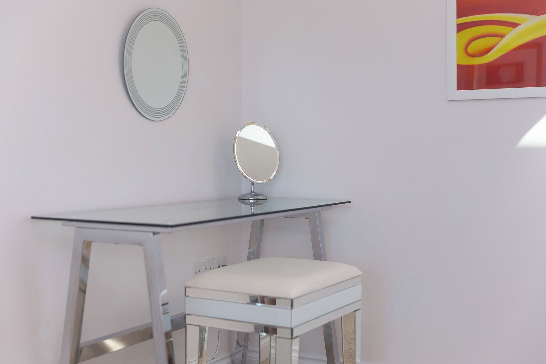 A white vanity table with a mirror and a cushioned stool.