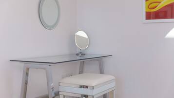 A white vanity table with a mirror and a cushioned stool.