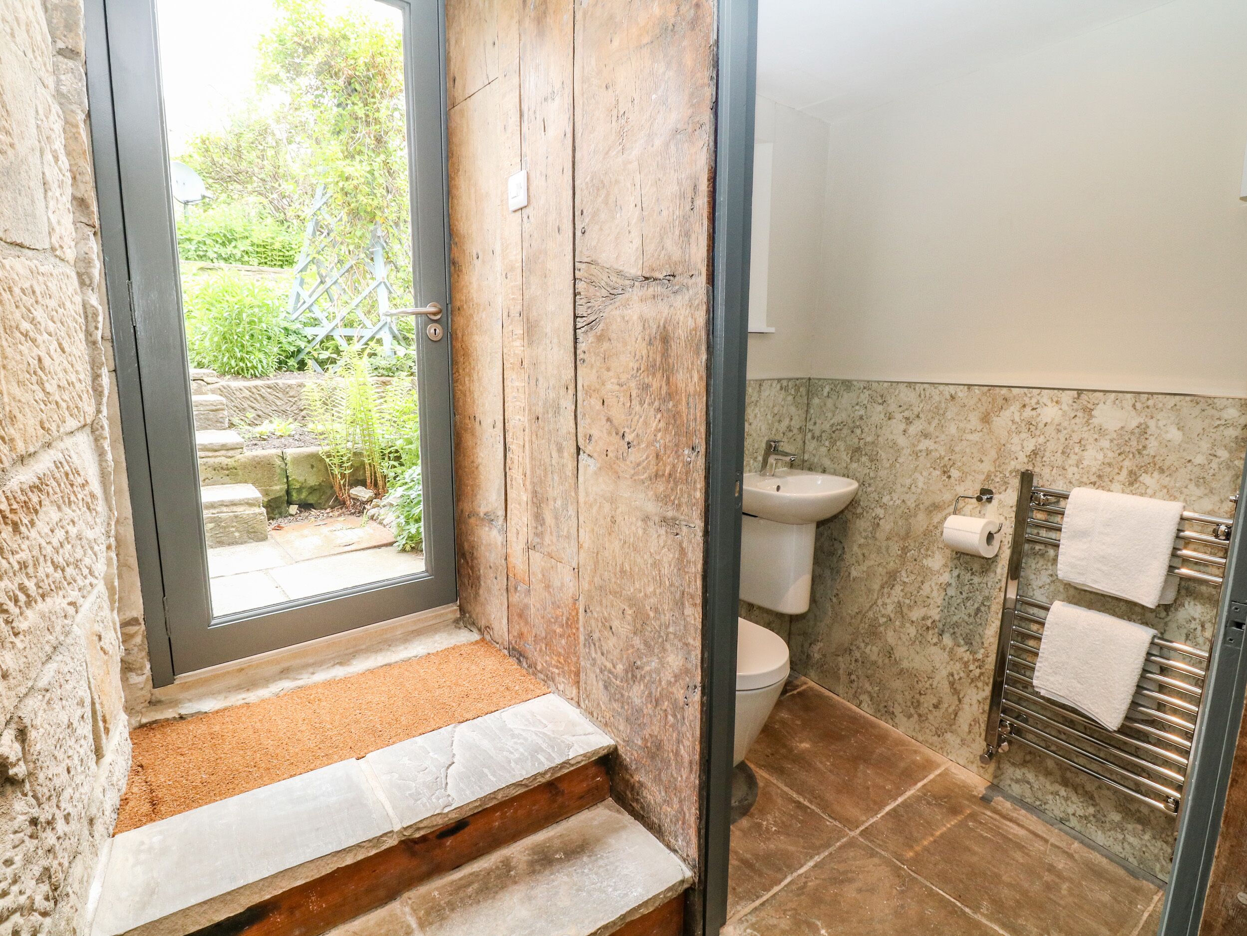 Un baño con pared de piedra, un lavabo, un inodoro y un perchero para toallas.