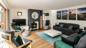 A modern living room with a fireplace, a sofa, a TV, and a coffee table. - Iroko (Torpoint)