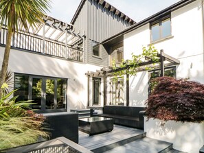 A modern two-story house with a patio, outdoor seating, and a pergola. - Iroko (Torpoint)