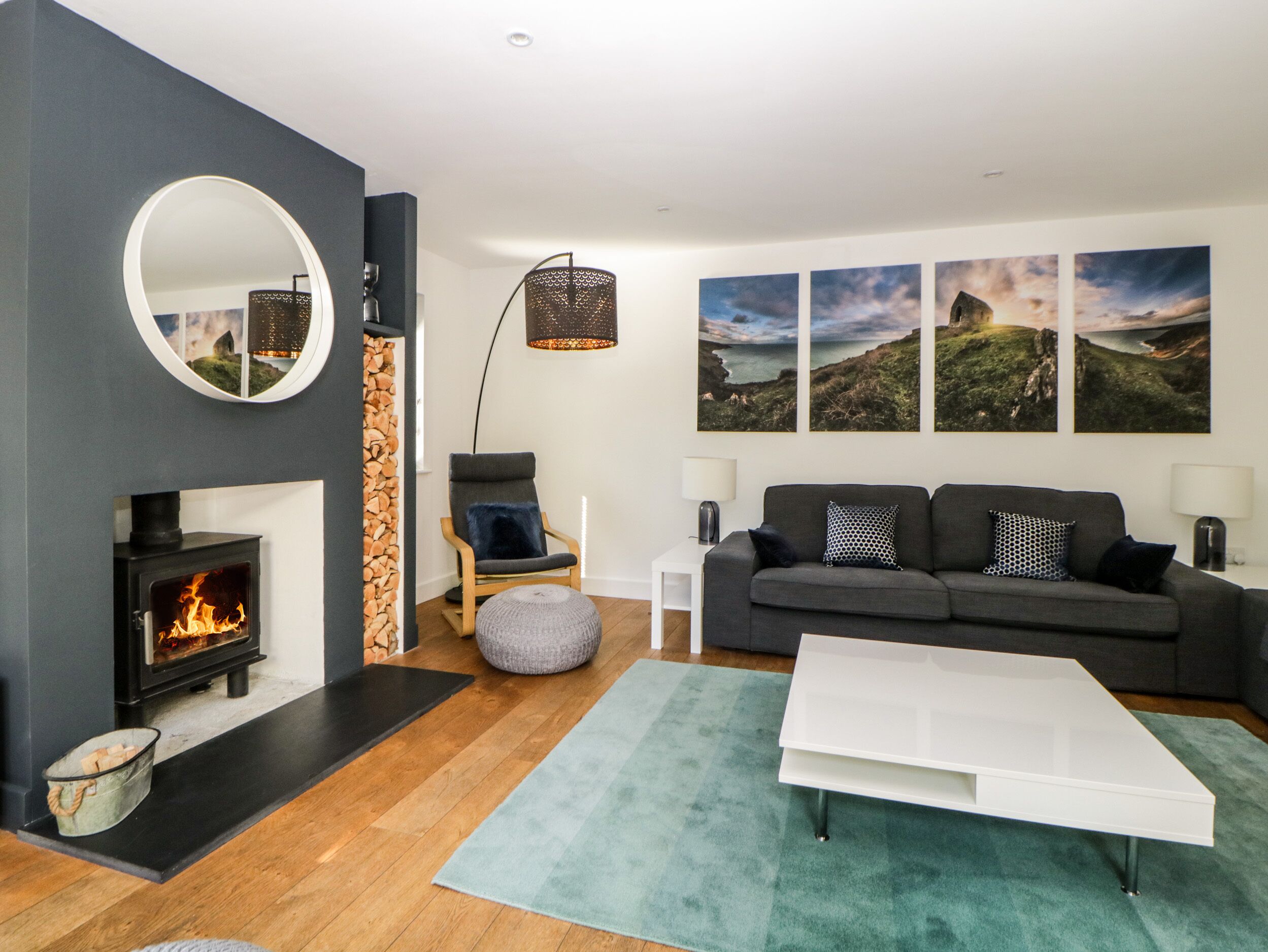 Una sala de estar moderna con chimenea, un sofá gris, una mesa de centro blanca y una alfombra verde.