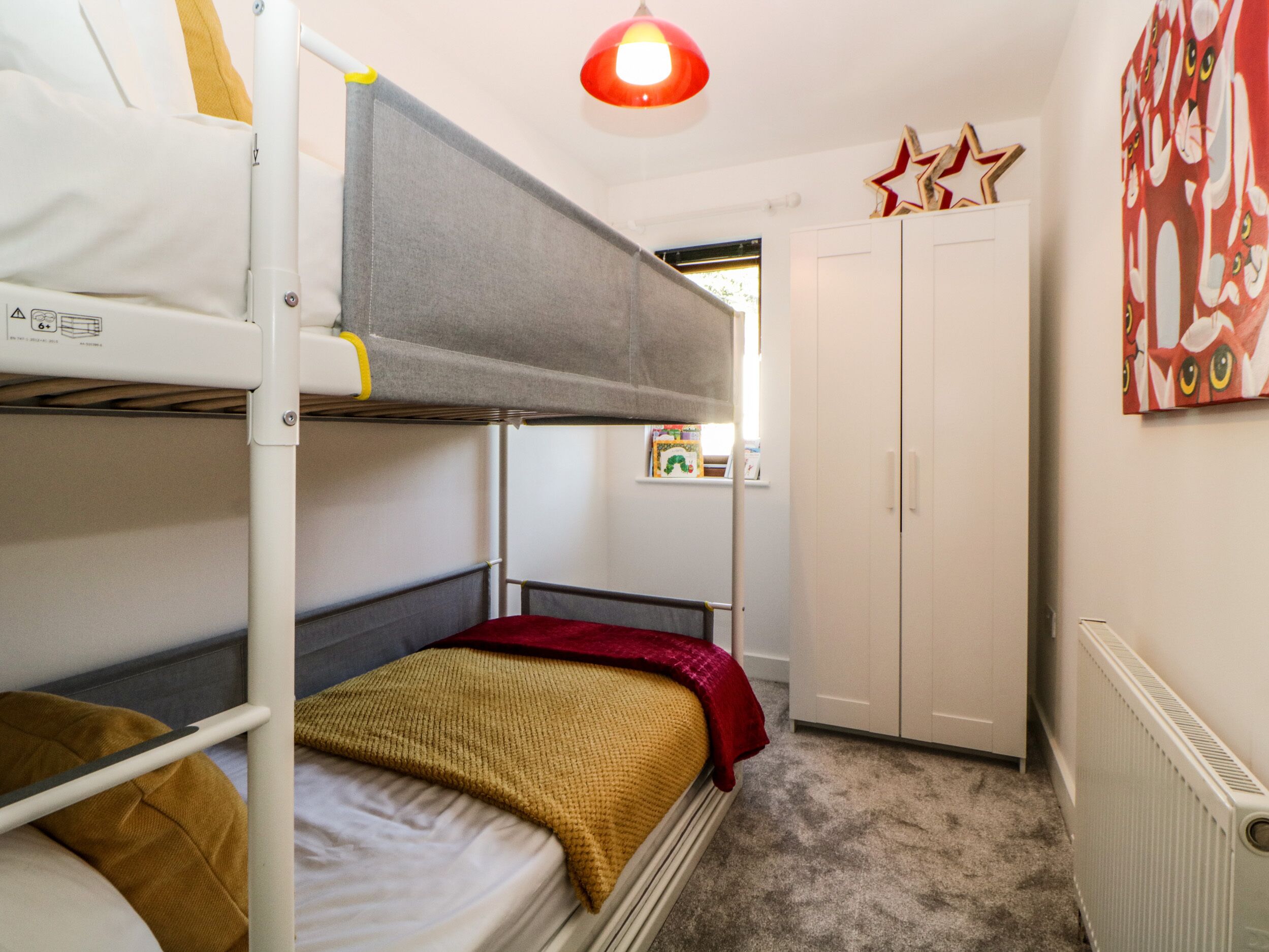Une chambre avec un lit superposé, un radiateur, une armoire et une fenêtre donnant sur l’extérieur.