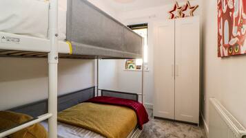 Une chambre avec un lit superposé, un radiateur, une armoire et une fenêtre donnant sur l’extérieur.