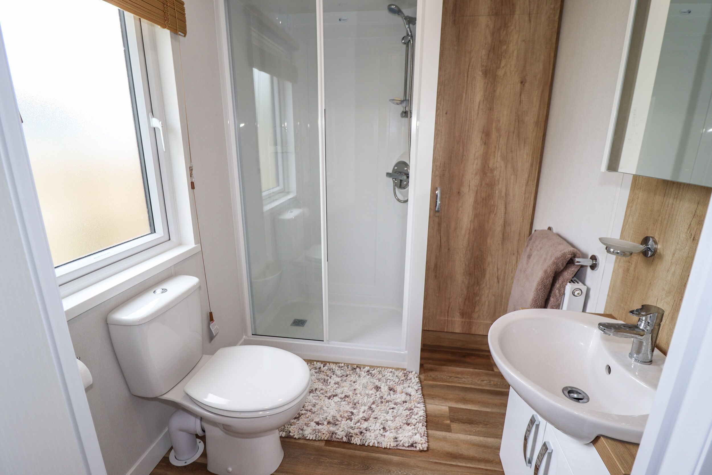 Une salle de bain comprenant des toilettes, une douche, un lavabo et une fenêtre.
