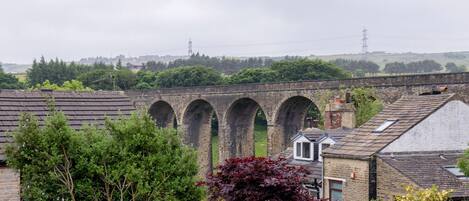A view of a brick bridge with multiple arches, surrounded by residential buildings and greenery.