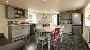 Una cocina moderna con armarios grises, un refrigerador de acero inoxidable y una mesa de comedor con cuatro sillas.