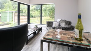 Un salon moderne avec un canapé, une table basse en verre et une bouteille de vin.