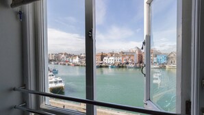 A view from a window overlooking a harbor with boats, buildings, and a clear sky. - Harbourside Cottage (Weymouth)