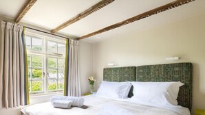 Ein Hotelzimmer mit einem großen Bett und Blick auf grüne Vegetation, gestaltet in einem schlichten, klaren Stil.
