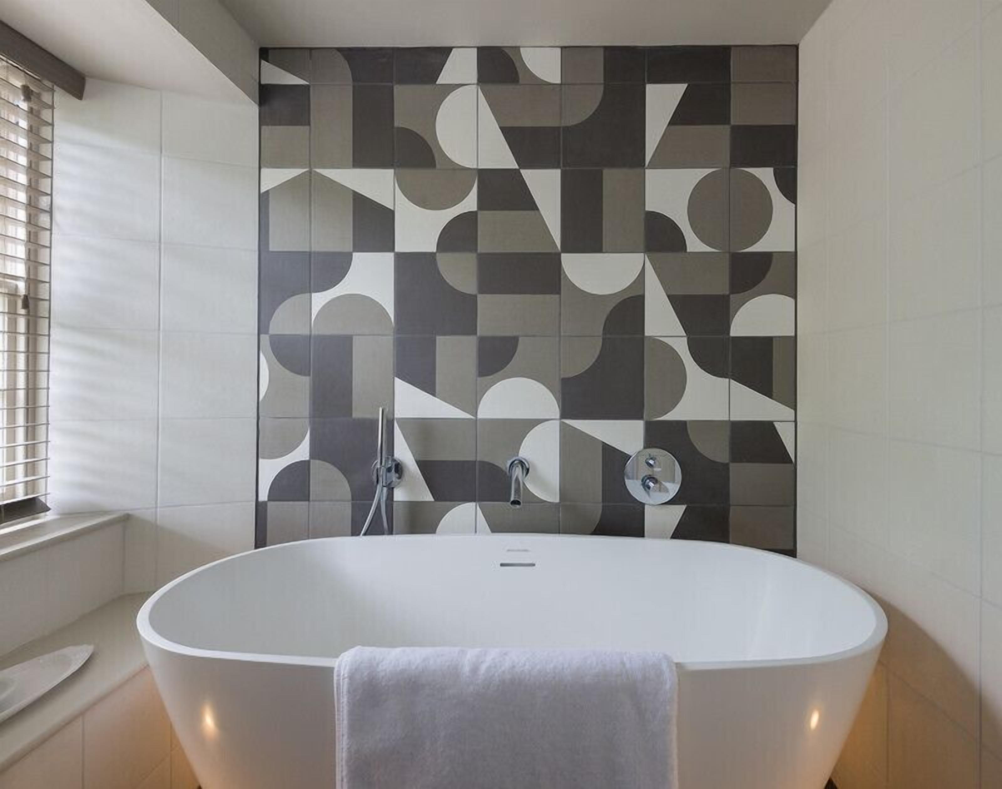 A modern bathroom with a freestanding bathtub, a shower, and a patterned wall.