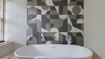 A modern bathroom with a freestanding bathtub, a shower, and a patterned wall.