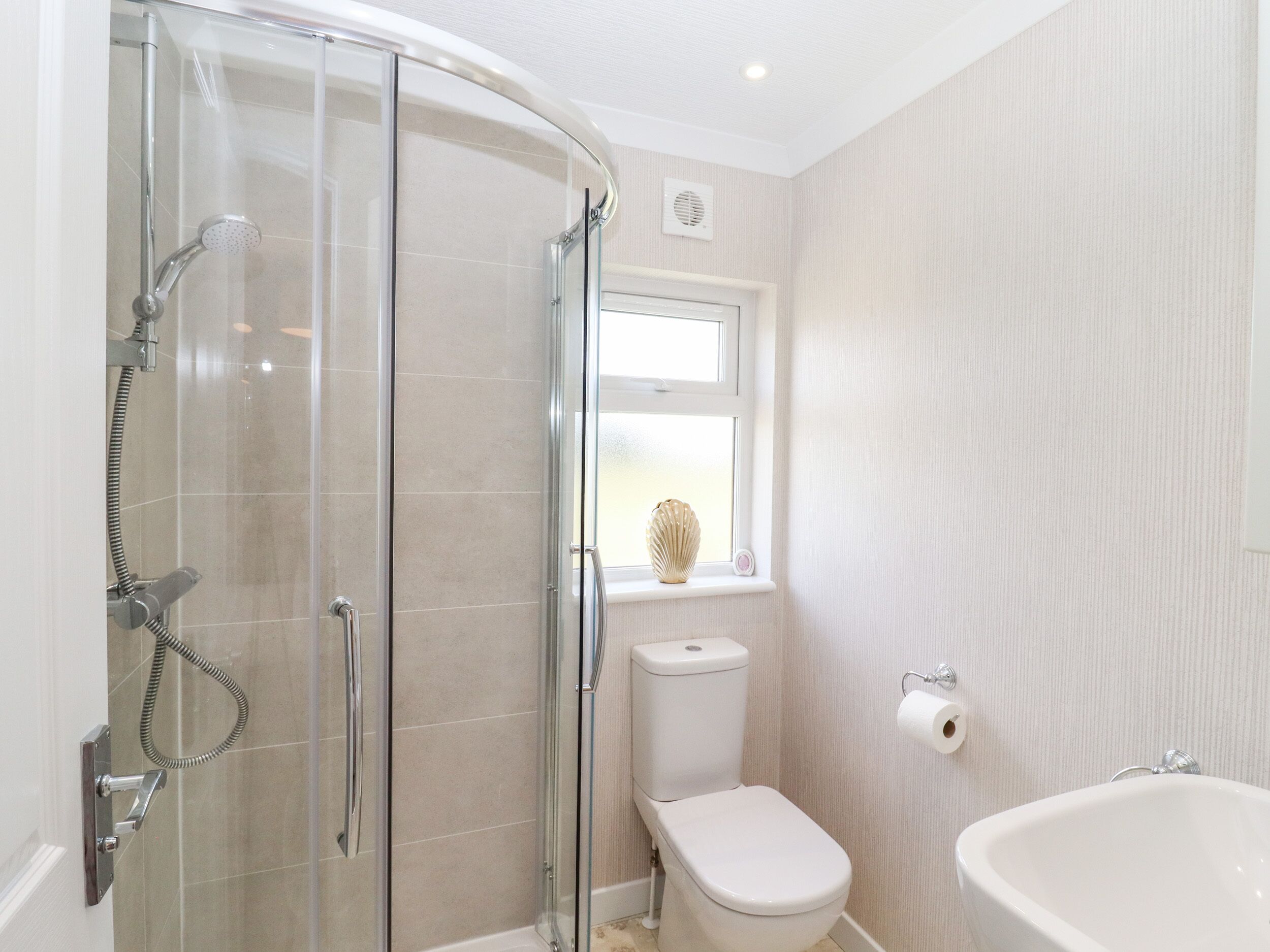 A modern bathroom with a glass shower enclosure, a toilet, and a bathtub.