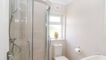 A modern bathroom with a glass shower enclosure, a toilet, and a bathtub.