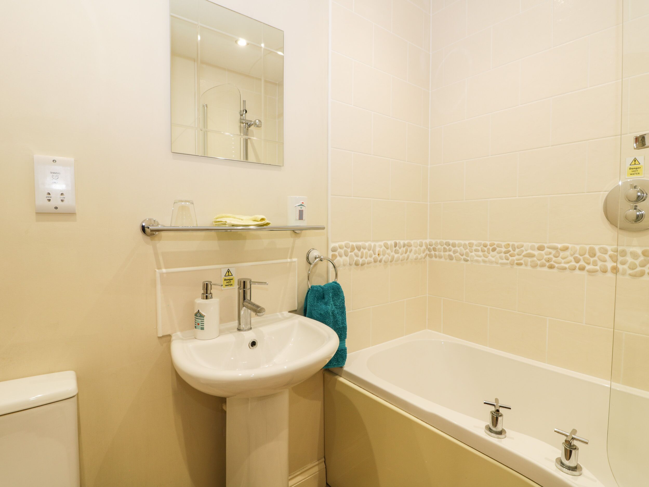 A bathroom with a sink, mirror, and bathtub.