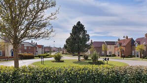 A residential street with houses, a roundabout, and well-maintained hedges. - Puffin Cottage (Filey)