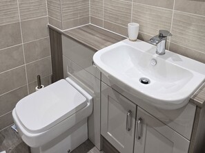 A bathroom with a toilet, a sink, and a roll of toilet paper.