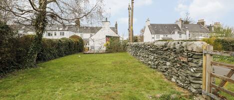 A stone wall, a wooden gate, and a grassy area with a small shed.