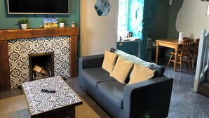 Ein Wohnzimmer mit Kamin, einer Couch, einem Tisch und einem an der Wand befestigten Fernseher.