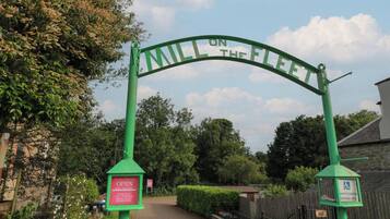 A green archway with the text "MILL ON THE FLEET" and a sign below stating "OPEN 10AM-4PM DAILY EXHIBITION CAFE BOOKSHOP ARTS & CRAFTS INFORMATION".