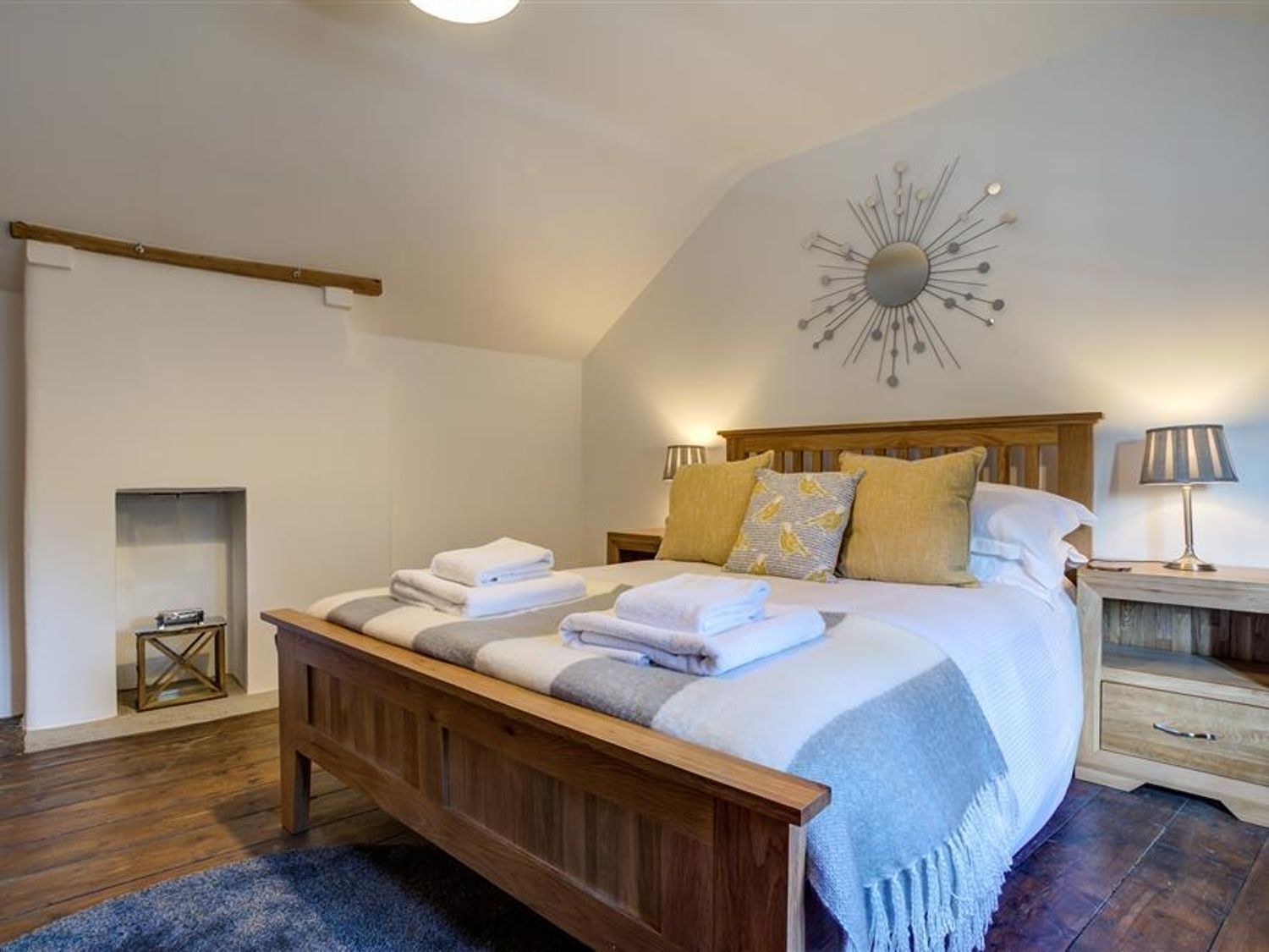 A bedroom with a wooden bed, a decorative wall piece, and a small fireplace.