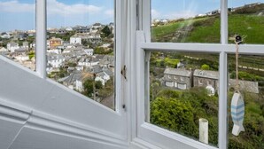Vista desde una ventana sobre un pueblo costero con casas y vegetación.