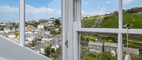 A view from a window overlooking a coastal town with houses and greenery.