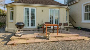 Une maison avec un patio, un barbecue et une table avec des chaises.