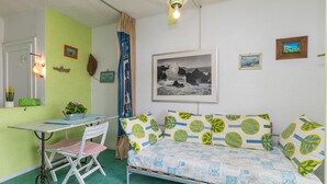 A room with a bed, a desk, and a chair. There is a ceiling fan, a picture on the wall, and a window with curtains. - Il Vecchio Faro A42 150m From The Beach (Loiri Porto San Paolo)