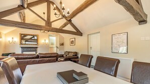 A dining area with a high wooden ceiling, a chandelier, and a table set for four. - Dales Croft Apartment (Buxton)