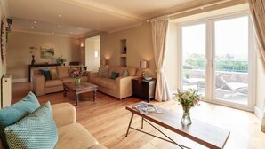 A spacious living room with a large window, a sofa, a coffee table, and a TV. - Worthy House (Wadebridge)