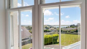 A view from a window with white frames and a skylight, overlooking a well-maintained garden and distant buildings. - The Haven (Wadebridge)