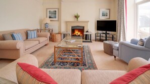 A living room with a fireplace, a television, and a sofa. - The Haven (Wadebridge)