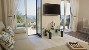 A modern living room with a sofa, a glass coffee table, a chessboard, and a TV mounted on the wall. - Crowthers (Dartmouth)