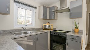 Cozinha equipada com pia, fogão, forno e micro-ondas.