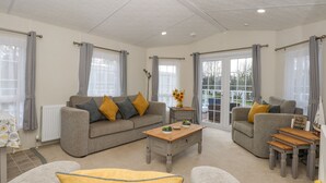 Uma sala de estar espaçosa com um sofá cinzento, uma mesa de centro e uma área de jantar com uma mesa de madeira e bancos.