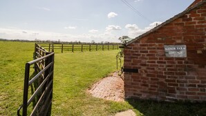 A brick building labeled "Manor Farm Cottage" with a paved path leading to a wooden gate. - Manor Farm Cottage (Worcester)
