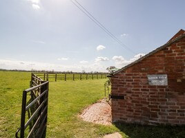 A brick building labeled "Manor Farm Cottage" with a paved path leading to a wooden gate.