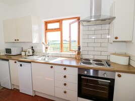 A modern kitchen with white cabinets, a built-in oven, a microwave, and a window with a view of the outdoors.