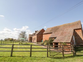 A brick farmstead with multiple buildings, a wooden fence, and a picnic area.