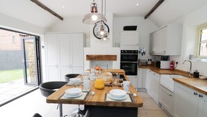 A modern kitchen with white cabinets, a wooden island, and a large window. - Hard Day's Night (Leicester)