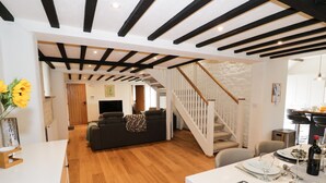 A spacious living area with a wooden floor, a sofa, a dining table set for two, and a staircase leading to another level. - Hard Day's Night (Leicester)