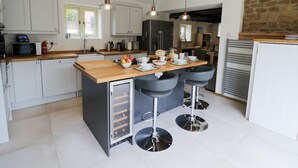 A modern kitchen with a central island, bar stools, and pendant lighting. - Hard Day's Night (Leicester)