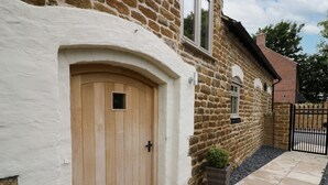 A stone house with a wooden door, a small window, and a black gate. - Hard Day's Night (Leicester)