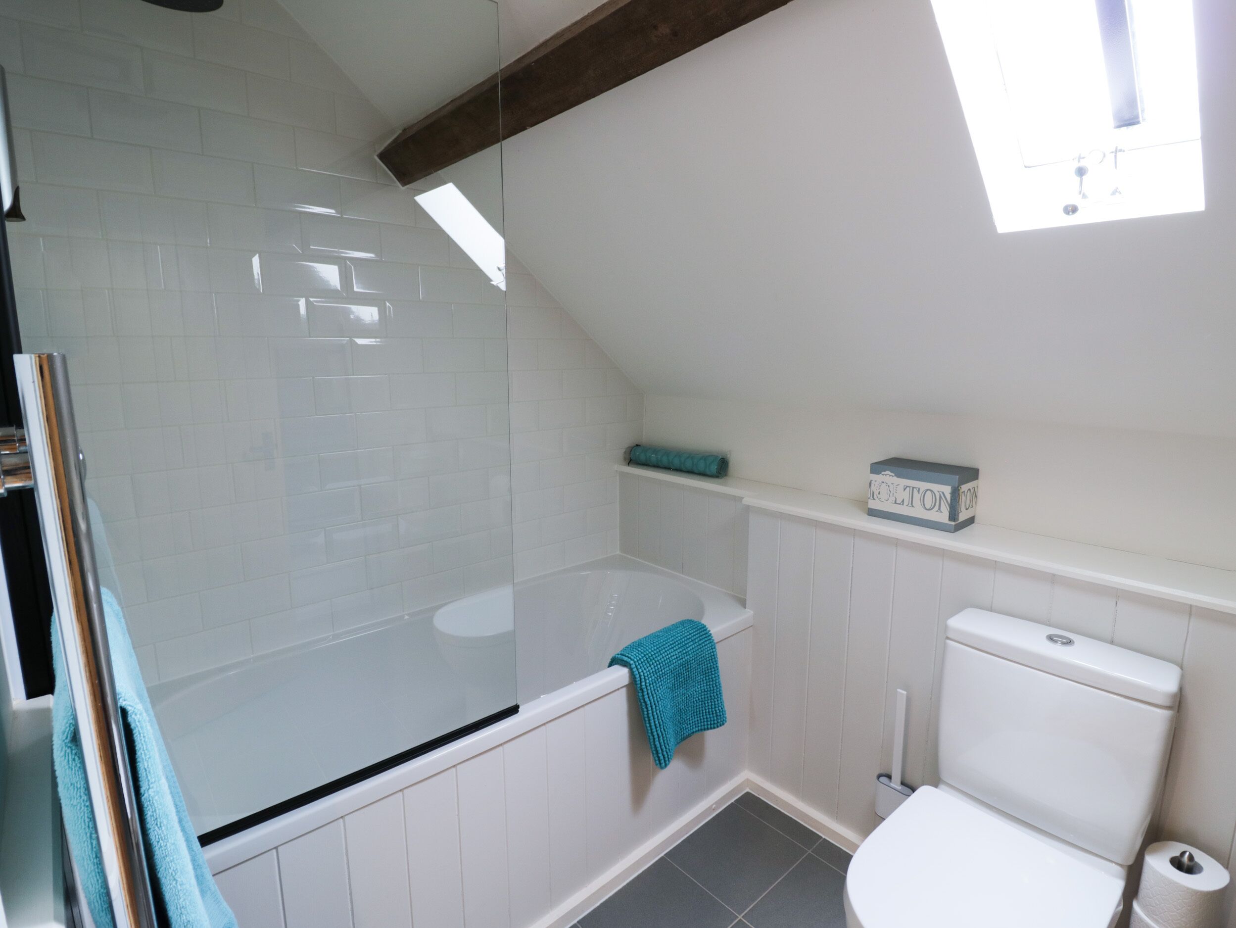 Un bagno con cabina doccia in vetro, una vasca, un water e uno scaffale con un asciugamano.