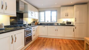 Une cuisine moderne avec des armoires blanches, des appareils en acier inoxydable et un plancher en bois.
