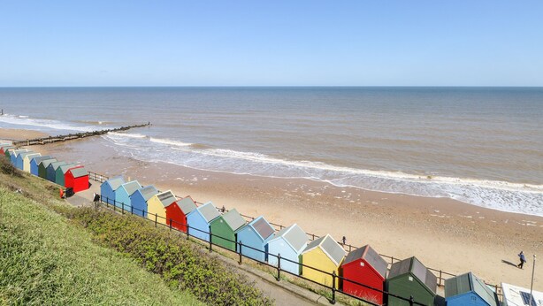 Une plage bordée de cabanes colorées et offrant une vue dégagée sur la mer.