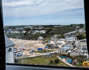 A coastal town with a sandy beach, residential houses, and a parking area. - Pinewood 14 (Wadebridge)