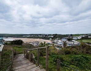 A coastal town with a beach, houses, and a staircase leading down to the beach. - Pinewood 14 (Wadebridge)