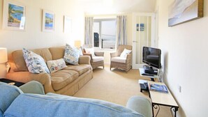 A cozy living room with a sofa, armchairs, a TV, and a dining table.